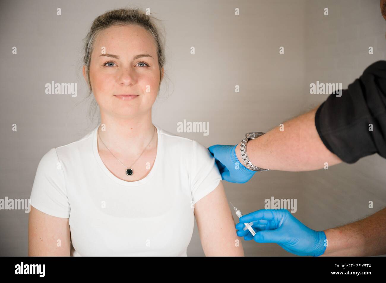 Medico che inietta il vaccino Covid in un braccio di pazienti: Curare la corona Pandemic con la vaccinazione di massa Foto Stock