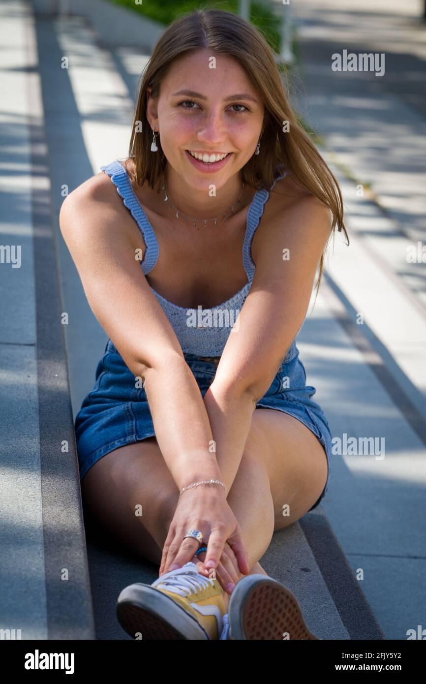 Ritratto di giovane donna seduta su lunghe scale di cemento Foto Stock
