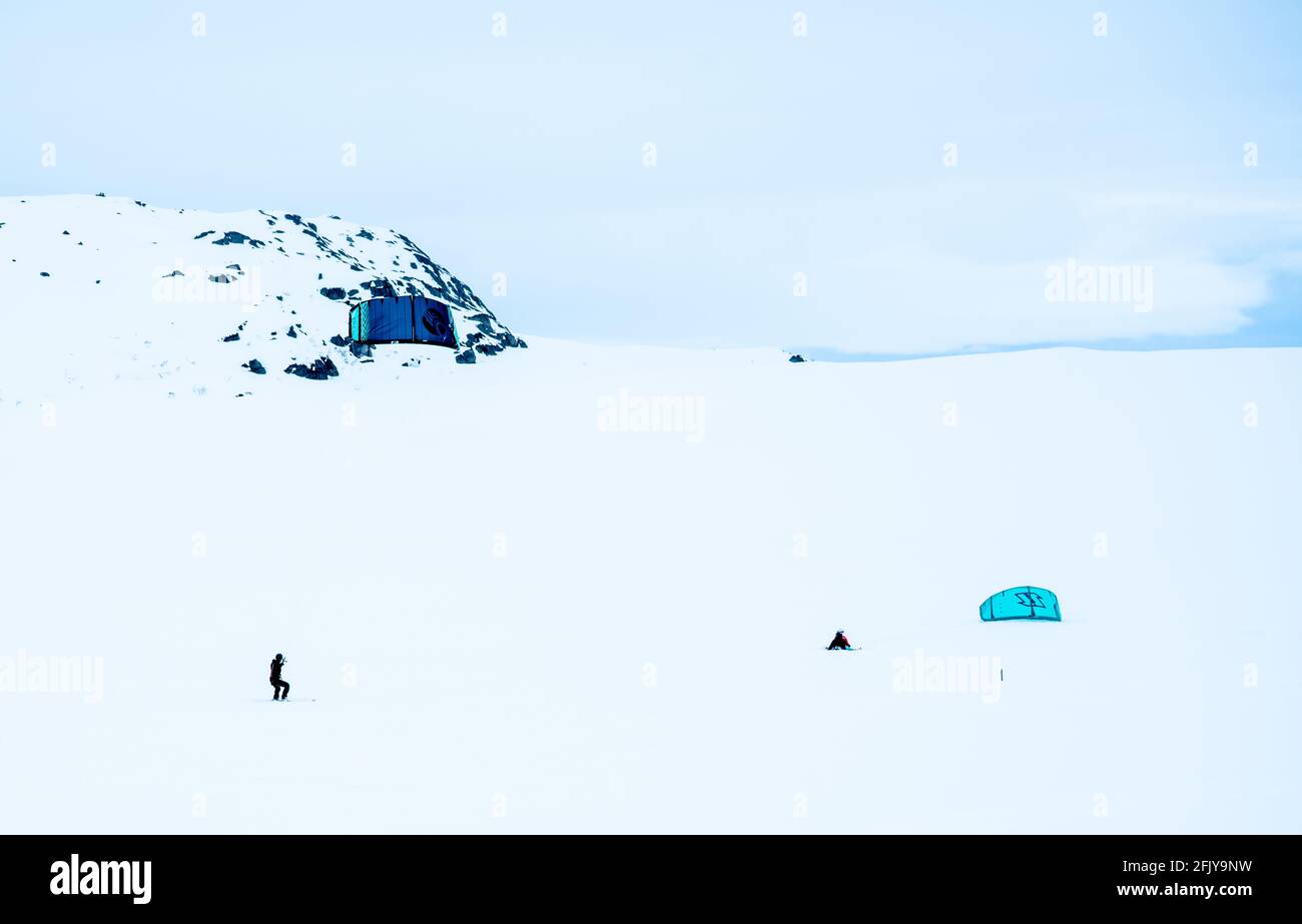 Persone Snowkiting su una pianura ghiacciata di montagna innevata in un freddo giorno di inverni. Foto Stock