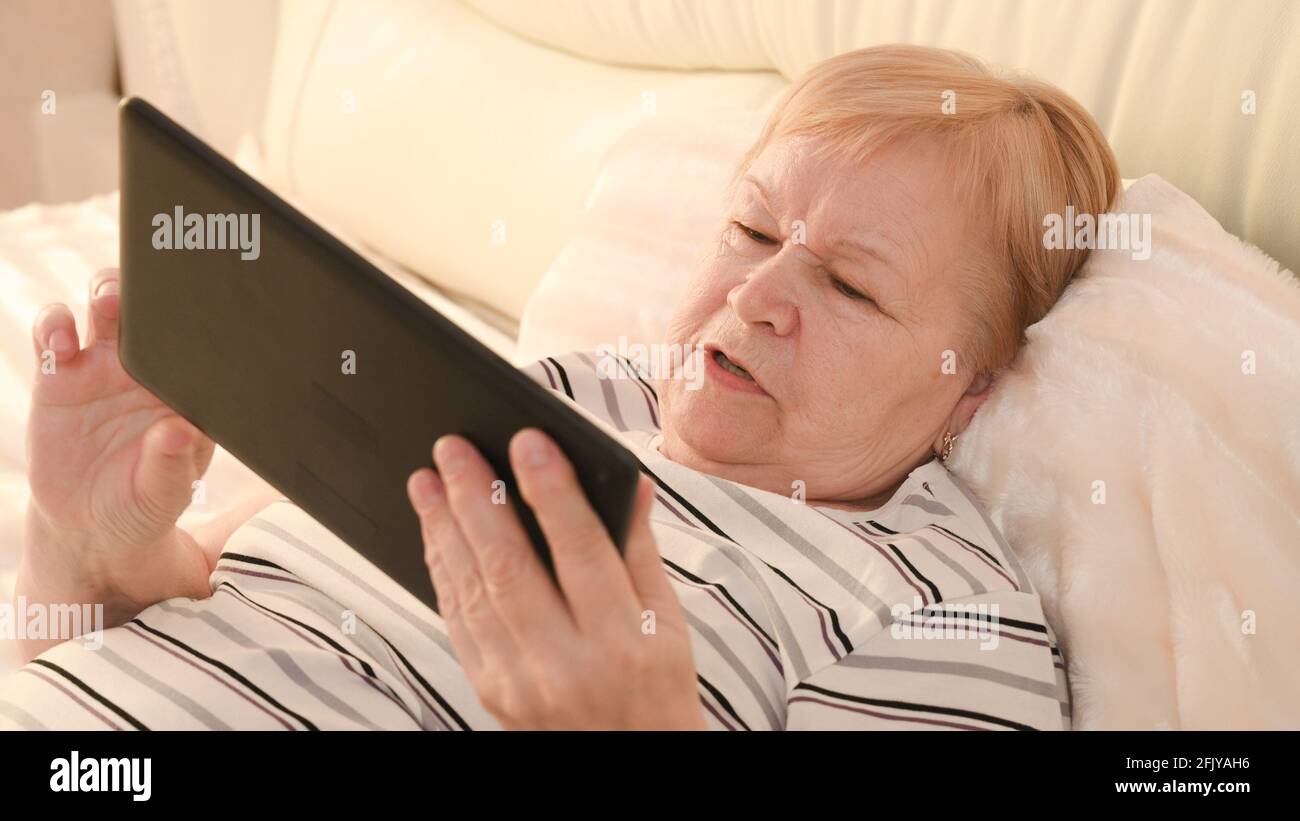 donna anziana con un dispositivo mobile in mano. Foto Stock