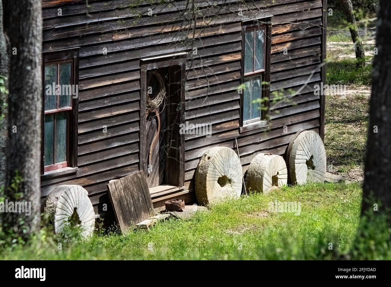 Opelika, Alabama, USA - 7 aprile 2021: Vecchie pietre del mulino che pende contro lo storico Bean's Mill situato su Halawakee Creek nella contea rurale di Lee nella Spri Foto Stock