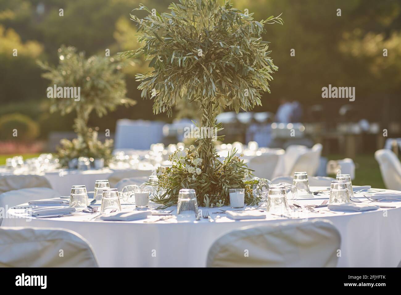 Matrimonio. Banchetto. Le sedie e il tavolo rotondo per gli ospiti, serviti  con posate, piccolo ulivo e coperti da una tovaglia bianca Foto stock -  Alamy