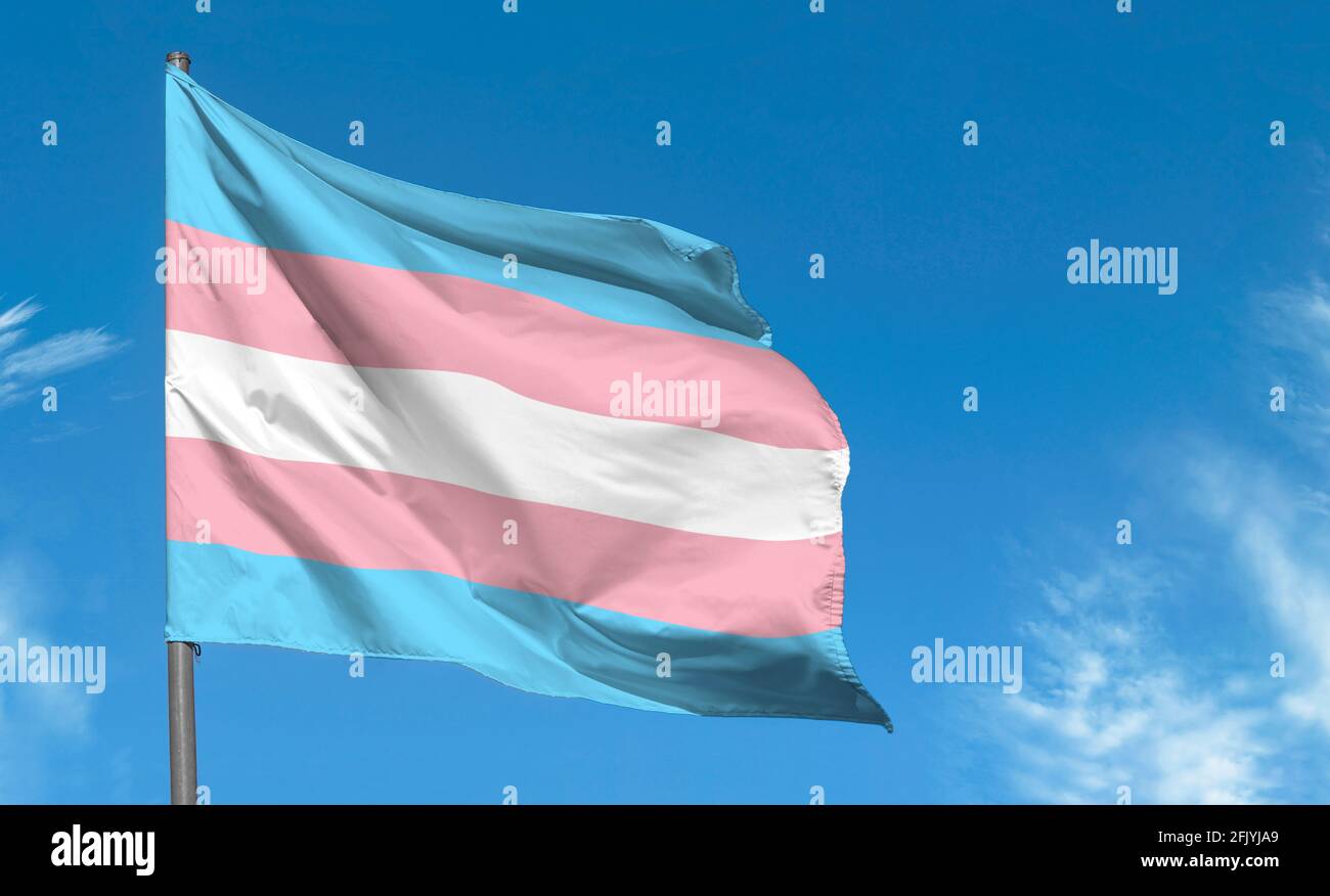 Bandiera transgender che oscilla contro il cielo blu, bandiera di orgoglio transgender in una strada Foto Stock