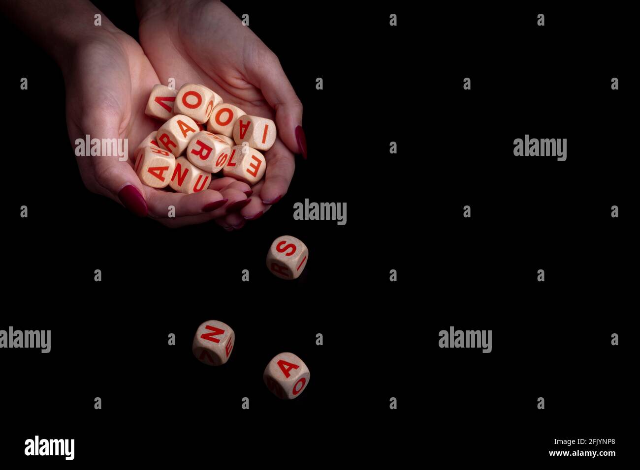 Le mani femminili tengono i dadi del giocattolo dell'alfabeto su sfondo nero e spazio di copia. Concetto di Dylexya Foto Stock