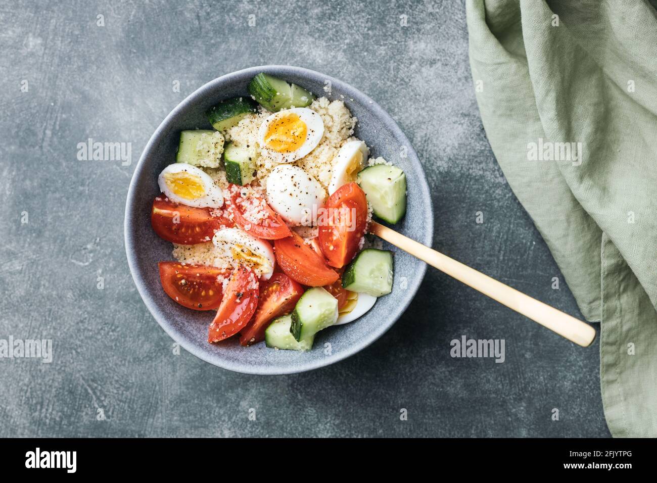 Ciotola per insalata di cous cous vegano con cetriolo, pomodori ciliegini e uova di quaglia su un tavolo di pietra. Foto Stock