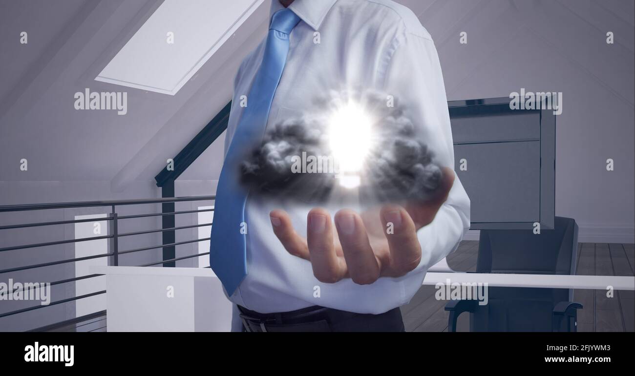 Composizione di lampadina illuminata con nuvole sulla mano dell'uomo d'affari in ufficio Foto Stock