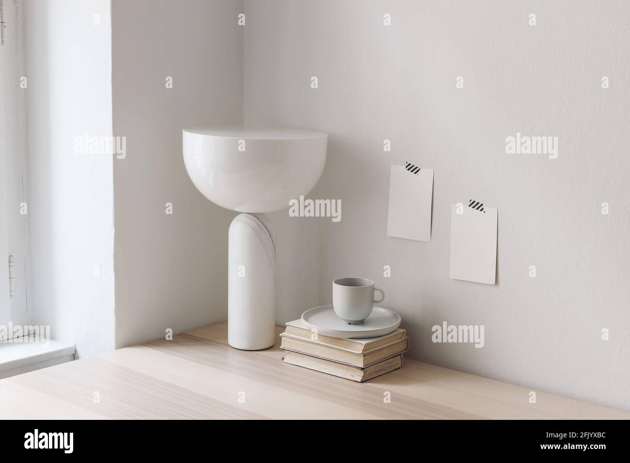 Colazione moderna ancora vita. Tazza di caffè, libri e lampada di marmo geometrico alla moda sul tavolo vicino alla finestra. Appunti vuoti e poster mockup su cui sono stati registrati Foto Stock