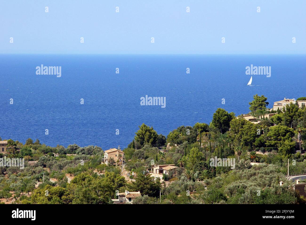 Un ampio colpo di cielo blu e mare con il villaggio di Deià in primo piano; Maiorca, Isole Baleari, Spagna. Pomeriggio di settembre. Foto Stock