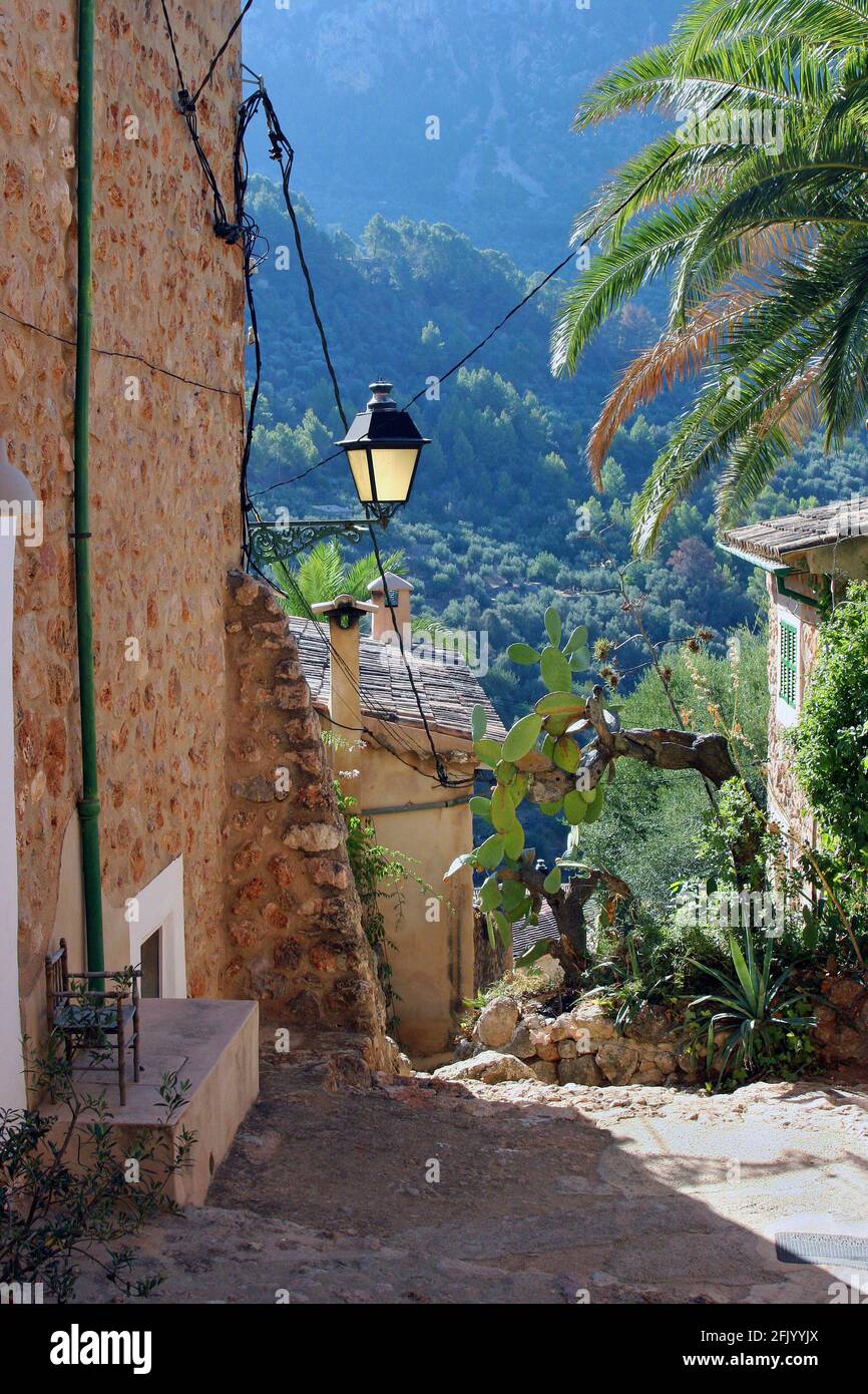 Una stradina nel villaggio collinare di Mallorcan di Fornalutx, Isole Baleari, che guarda verso la catena montuosa di Tramuntana. Una mattina di settembre. Foto Stock