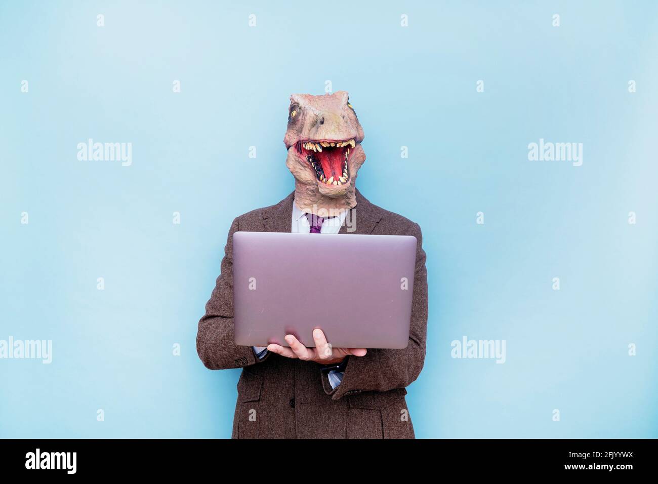 Uomo euforico con testa di lucertola con computer portatile su sfondo blu Foto Stock