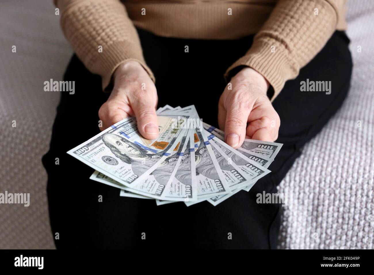 Donna anziana con dollari USA in mani stropicciate da vicino. Concetto di pagamento delle pensioni, risparmio al pensionamento, vincitore, pensionato con denaro Foto Stock
