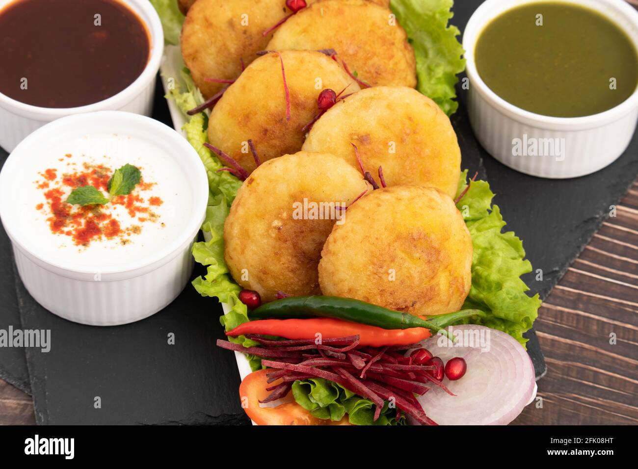 Alo Tikki, conosciuto anche come Alu Ki Tikkia, è condito Frittatine o frittatine di patate bollite usate in vari indiani Cibo di strada Masala Chaat spuntini Foto Stock