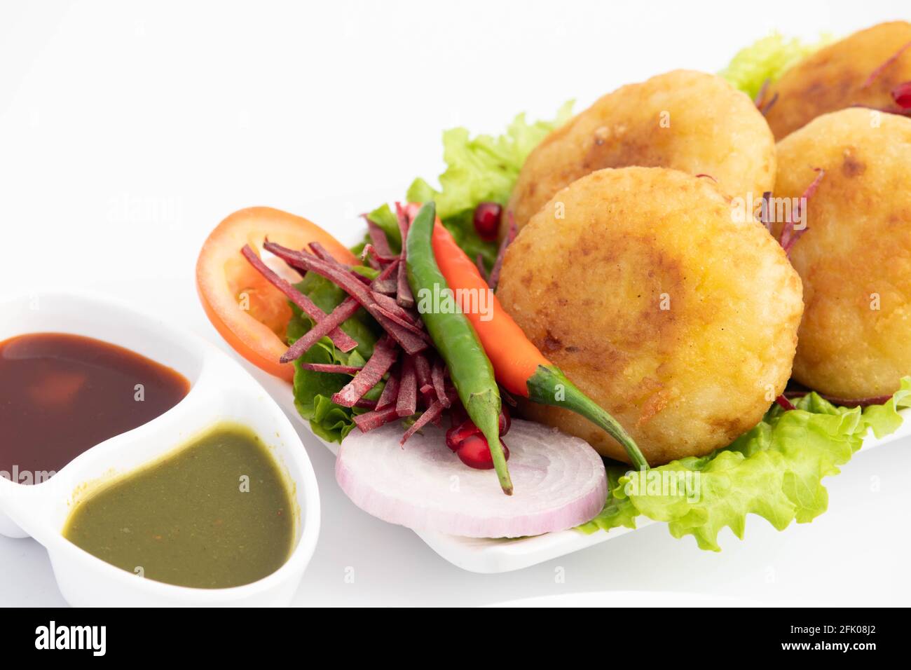 Alo Tikki, conosciuto anche come Alu Ki Tikkia, è condito Frittatine o frittatine di patate bollite usate in vari indiani Cibo di strada Masala Chaat spuntini Foto Stock
