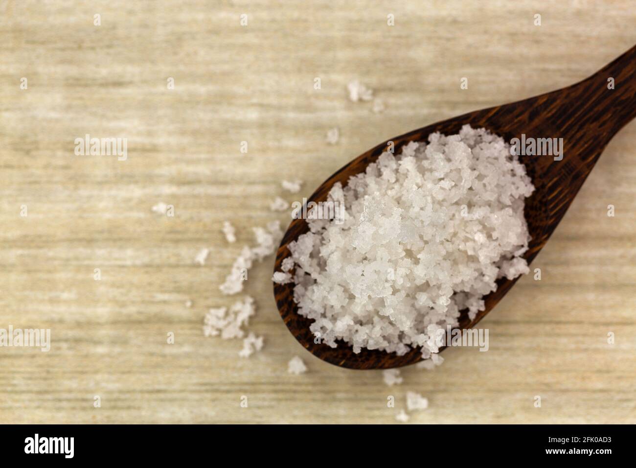 Fiore di sale, raccolto da strato sottile su superficie di acqua di mare, in cucchiaio di legno. Chiamato Fleur de sel in francese, vista dall'alto con copyspace Foto Stock