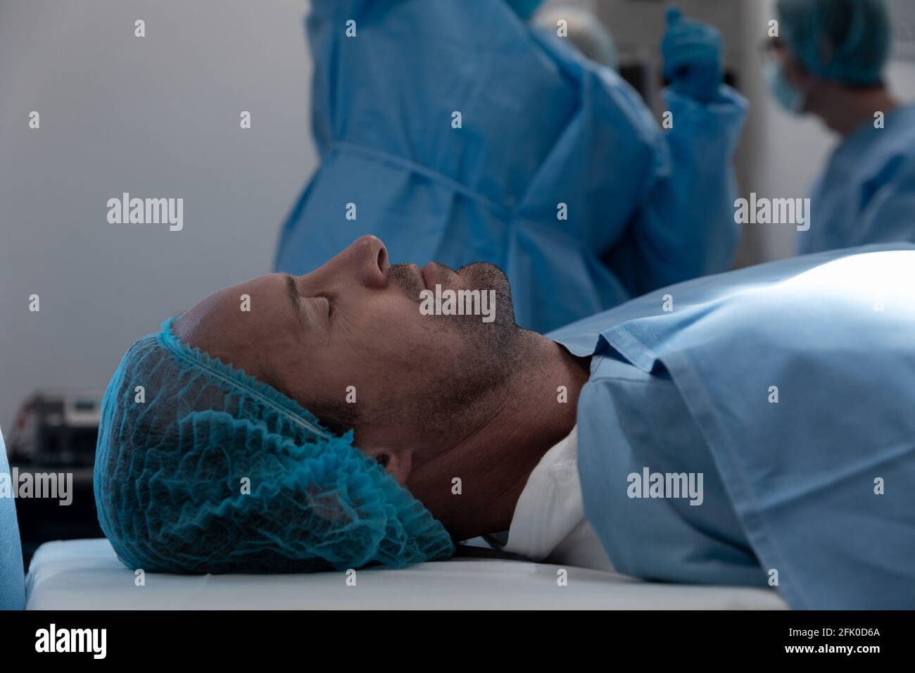 Paziente di sesso maschile caucasico sdraiato sul letto chirurgico in sala operatoria Foto Stock
