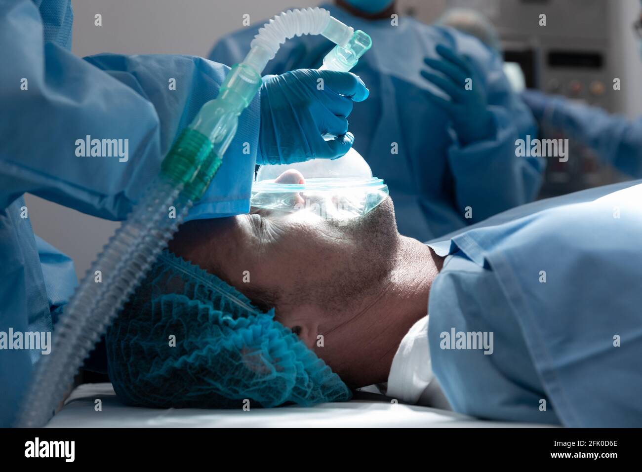 Paziente di sesso maschile caucasico sdraiato sul letto chirurgico con maschera di ossigeno in sala operatoria Foto Stock