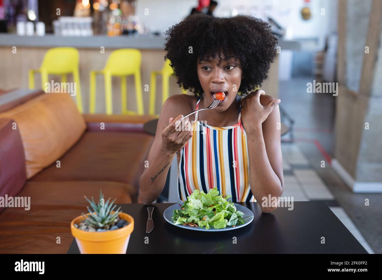 Donna afroamericana seduta al tavolo e mangiando in ristorante Foto Stock
