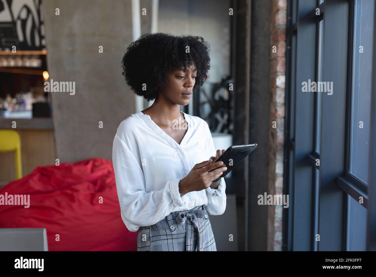 Donna afroamericana in piedi, utilizzando tablet e lavorando in un bar Foto Stock