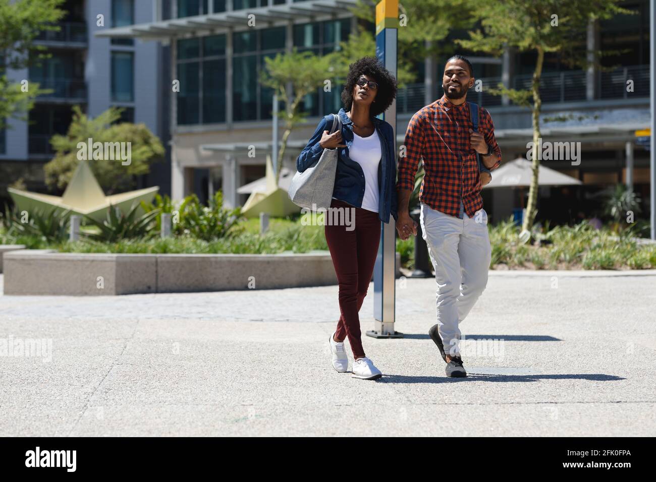 Razza mista uomo e donna afroamericana che cammina, tenendo le mani Foto Stock
