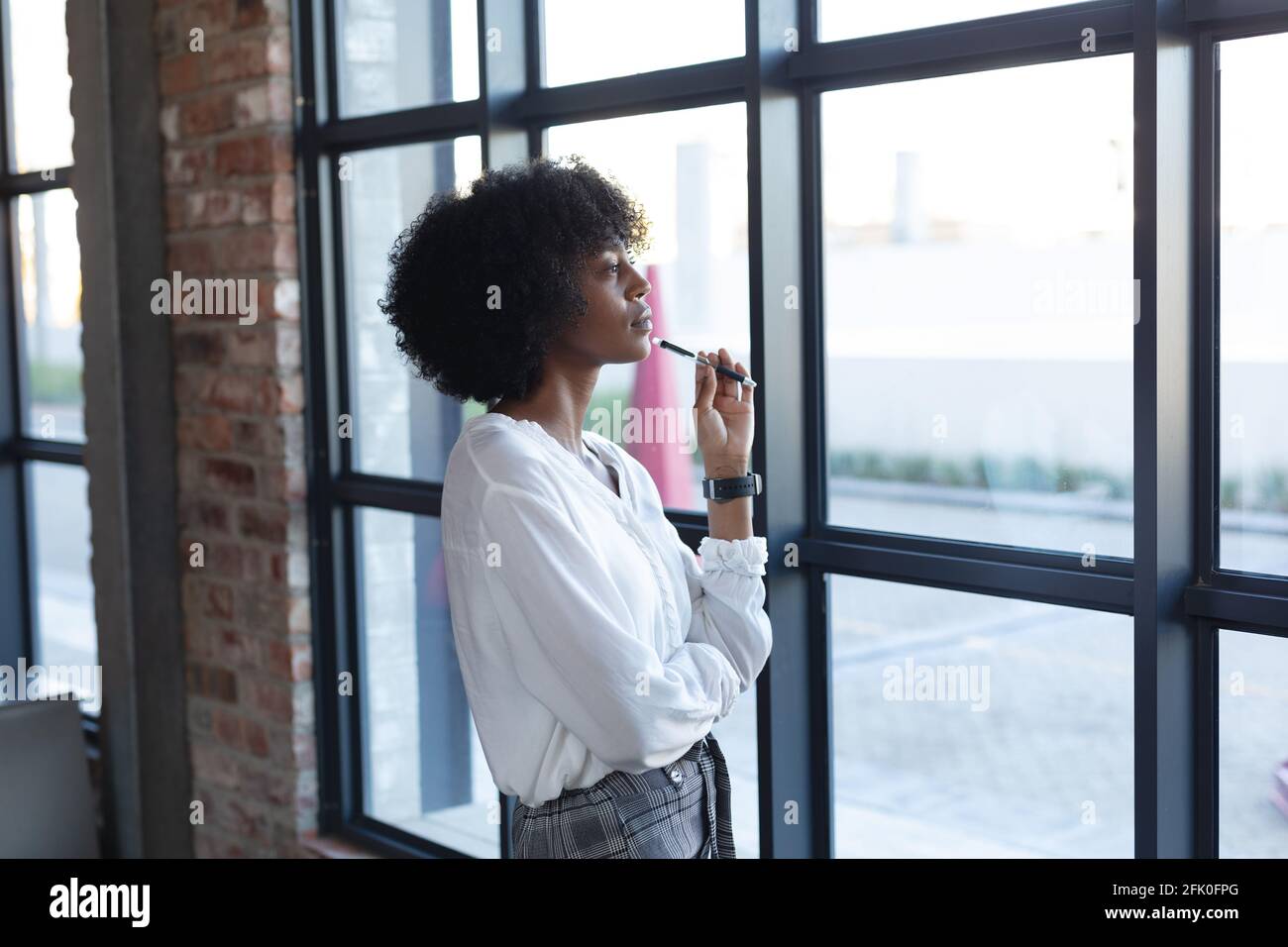 Donna afroamericana in piedi, tenendo la penna e pensando in caffetteria Foto Stock