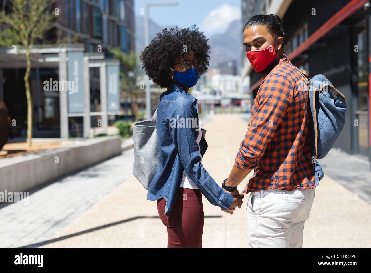 Razza mista uomo e donna afroamericana indossando maschere, tenendo le mani Foto Stock