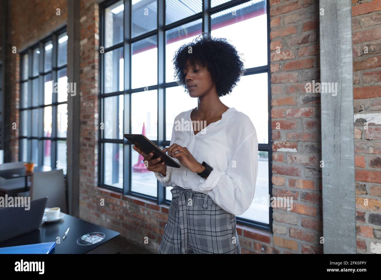 Donna afroamericana in piedi, utilizzando tablet e lavorando in un bar Foto Stock