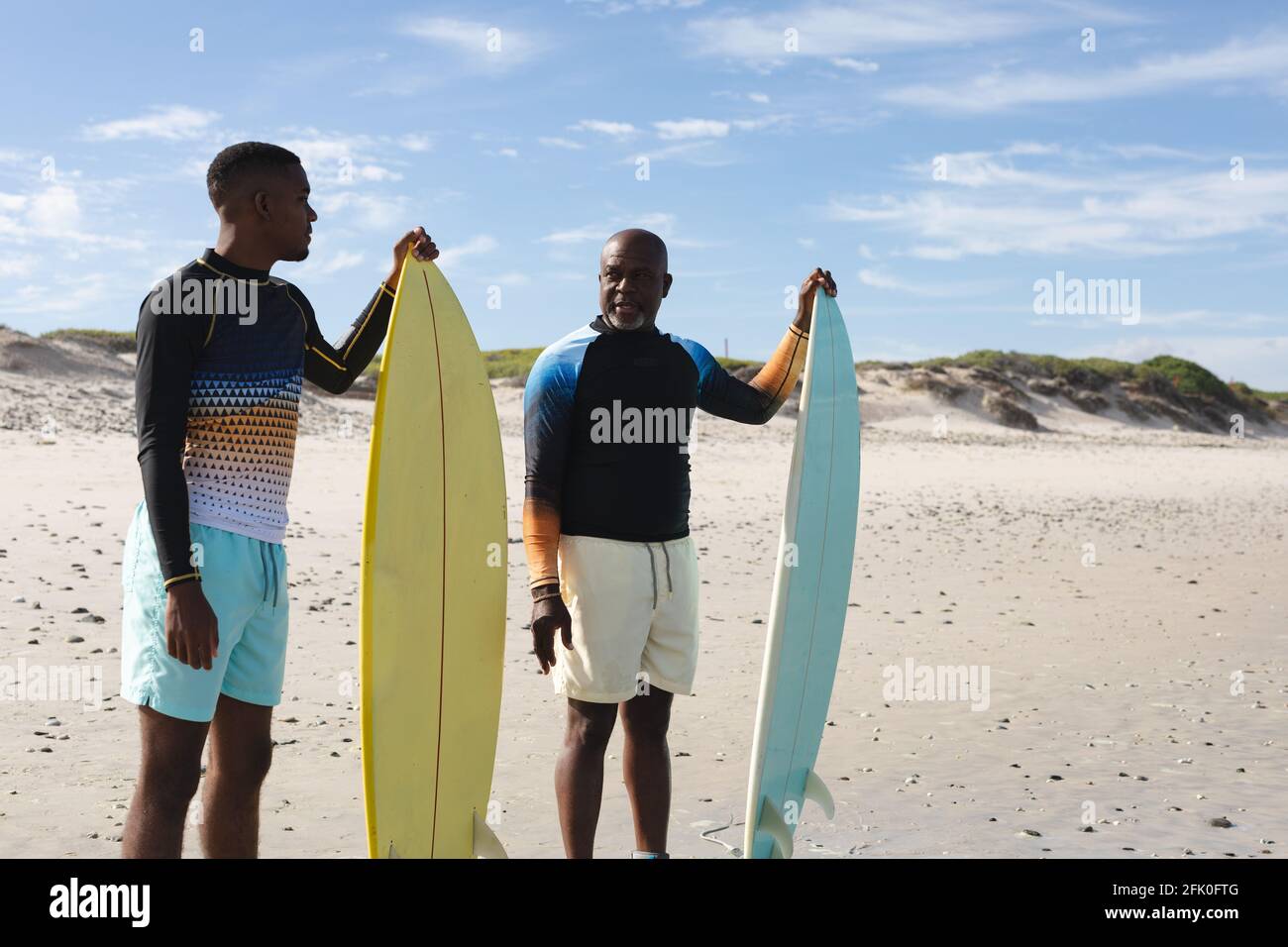 Padre e figlio afro-americano con tavole da surf in piedi al spiaggia Foto Stock