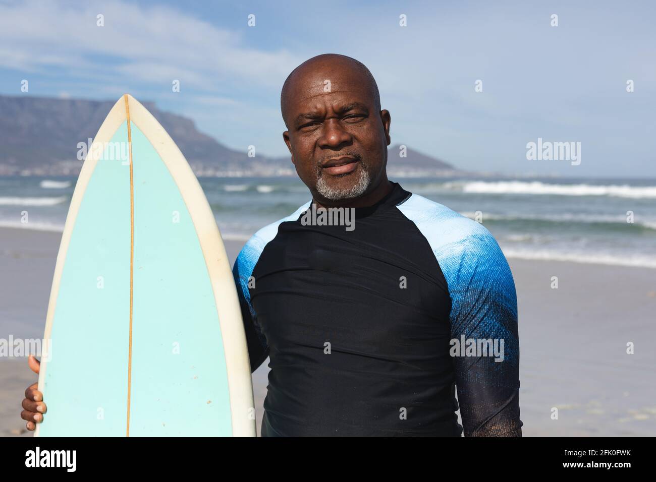 Ritratto di un anziano afro-americano con tavola da surf in piedi la spiaggia Foto Stock