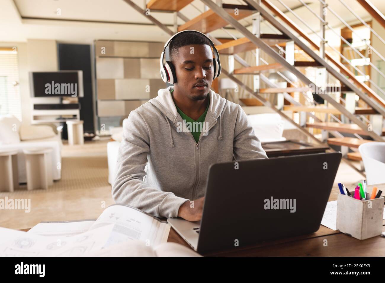 Giovane afroamericano che indossa le cuffie usando il laptop mentre studia a casa Foto Stock