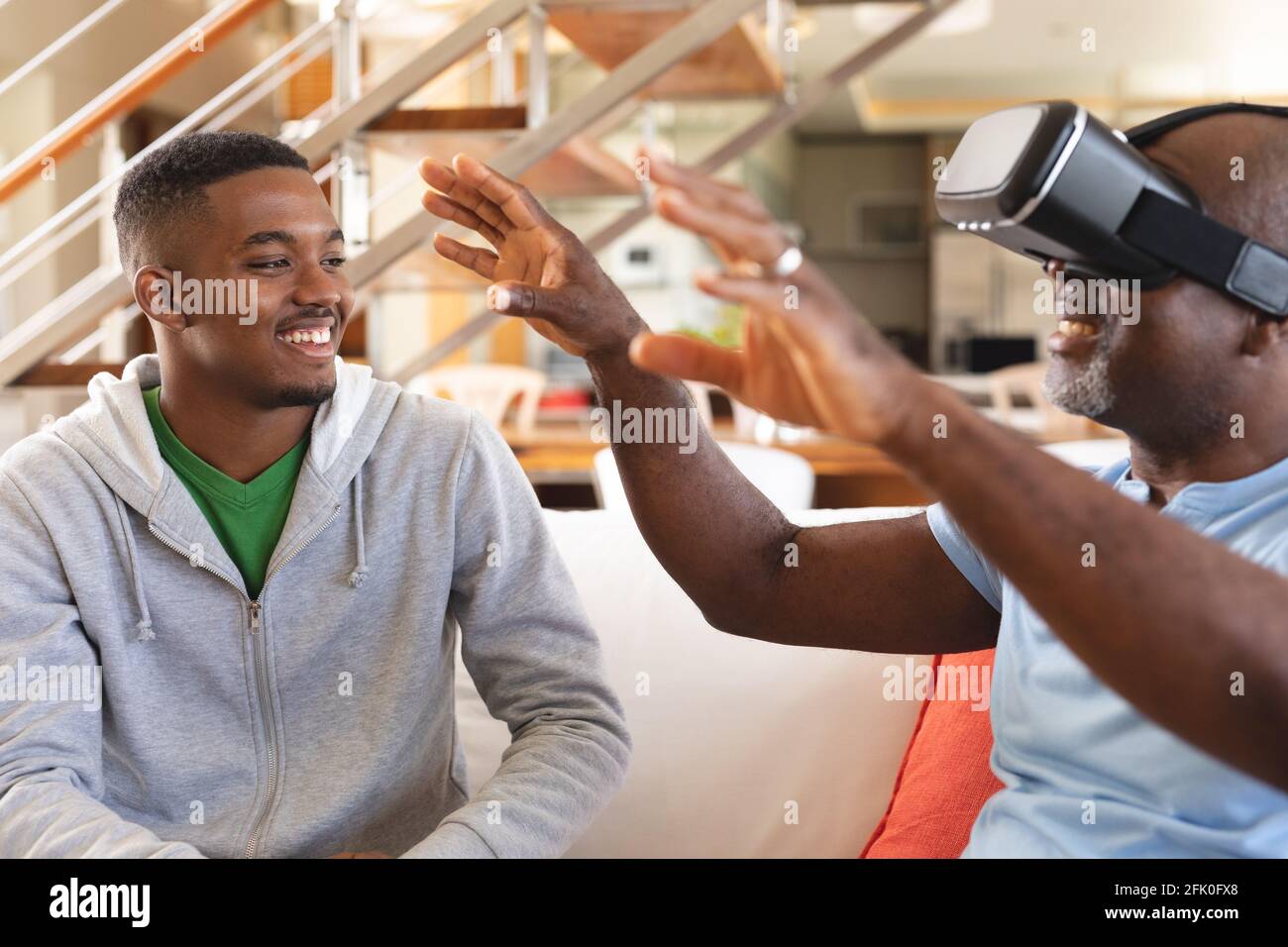 Giovane afro-americano che insegna al padre come usare visore vr a casa Foto Stock