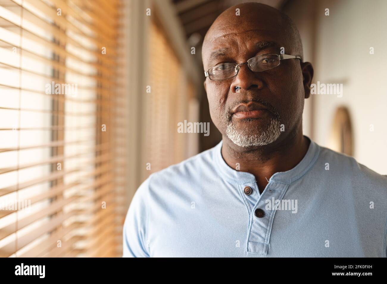 Ritratto di un uomo anziano afro-americano pensieroso in piedi a casa Foto Stock