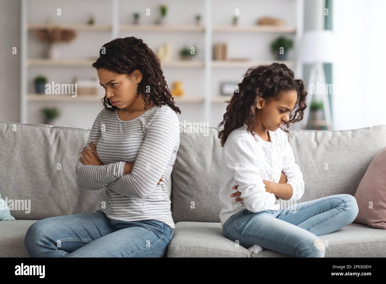Sconvolto madre afroamericana e figlia con le braccia incrociate su cassoni seduti sul divano a casa, sentirsi arrabbiato, copia spazio. Triste mamma nera e capretto havi Foto Stock