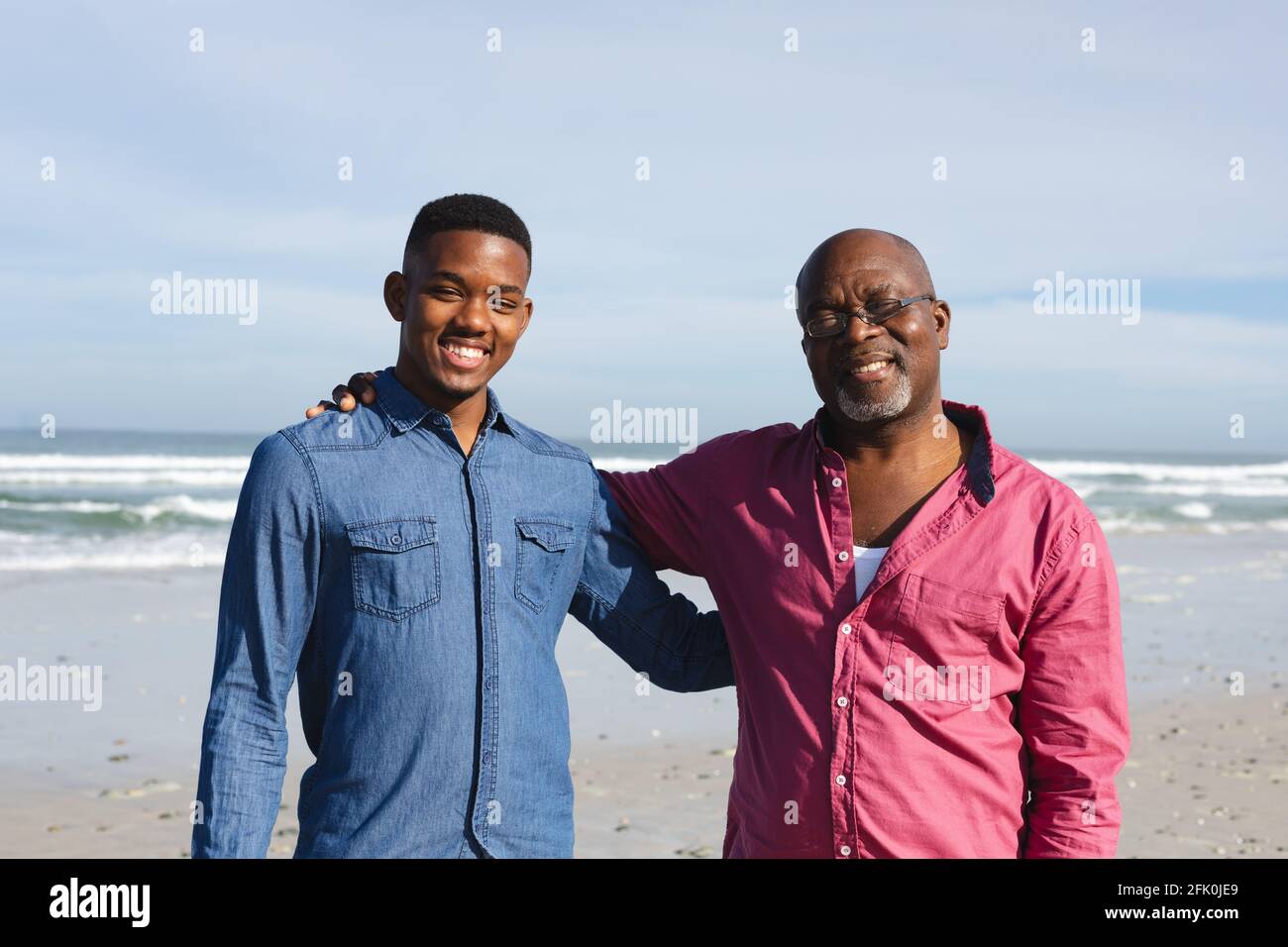 Ritratto di padre afroamericano e di suo figlio sorridente stare insieme in spiaggia Foto Stock