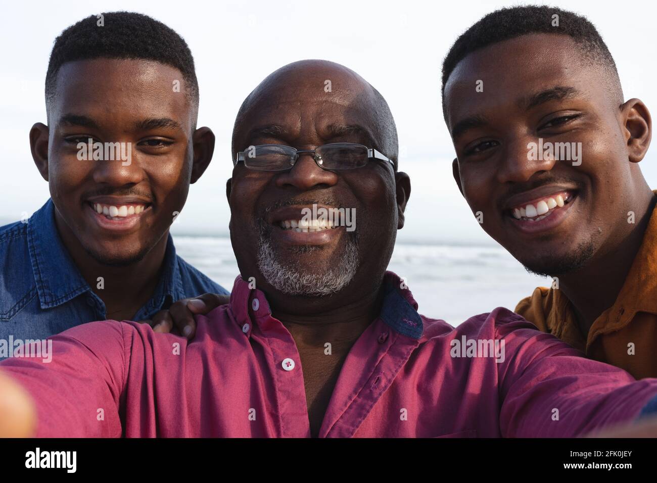 Ritratto di padre afroamericano e dei suoi due figli prendendo un selfie in spiaggia Foto Stock