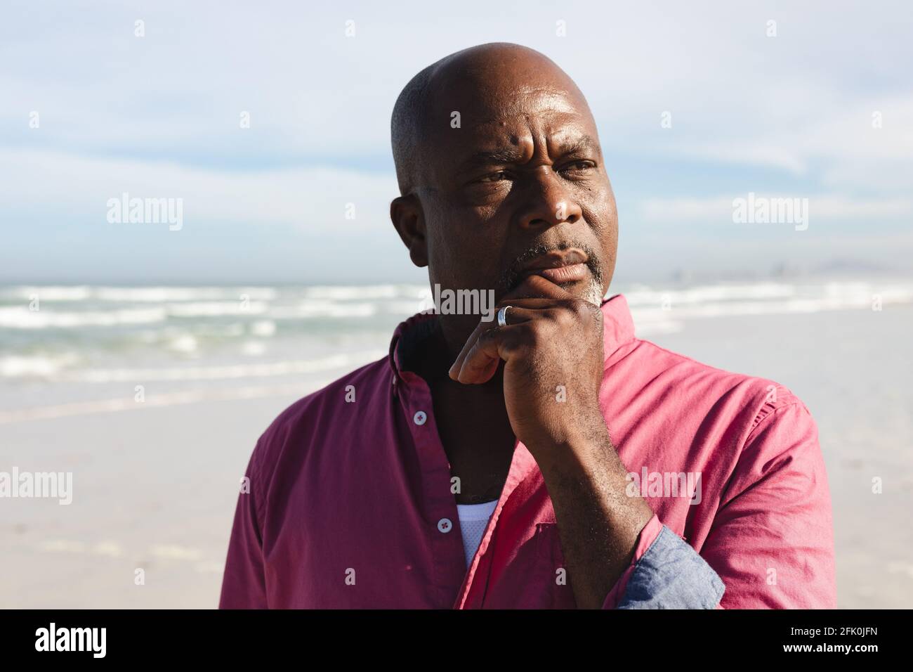 Uomo anziano afroamericano con la mano sul mento in piedi a. la spiaggia Foto Stock