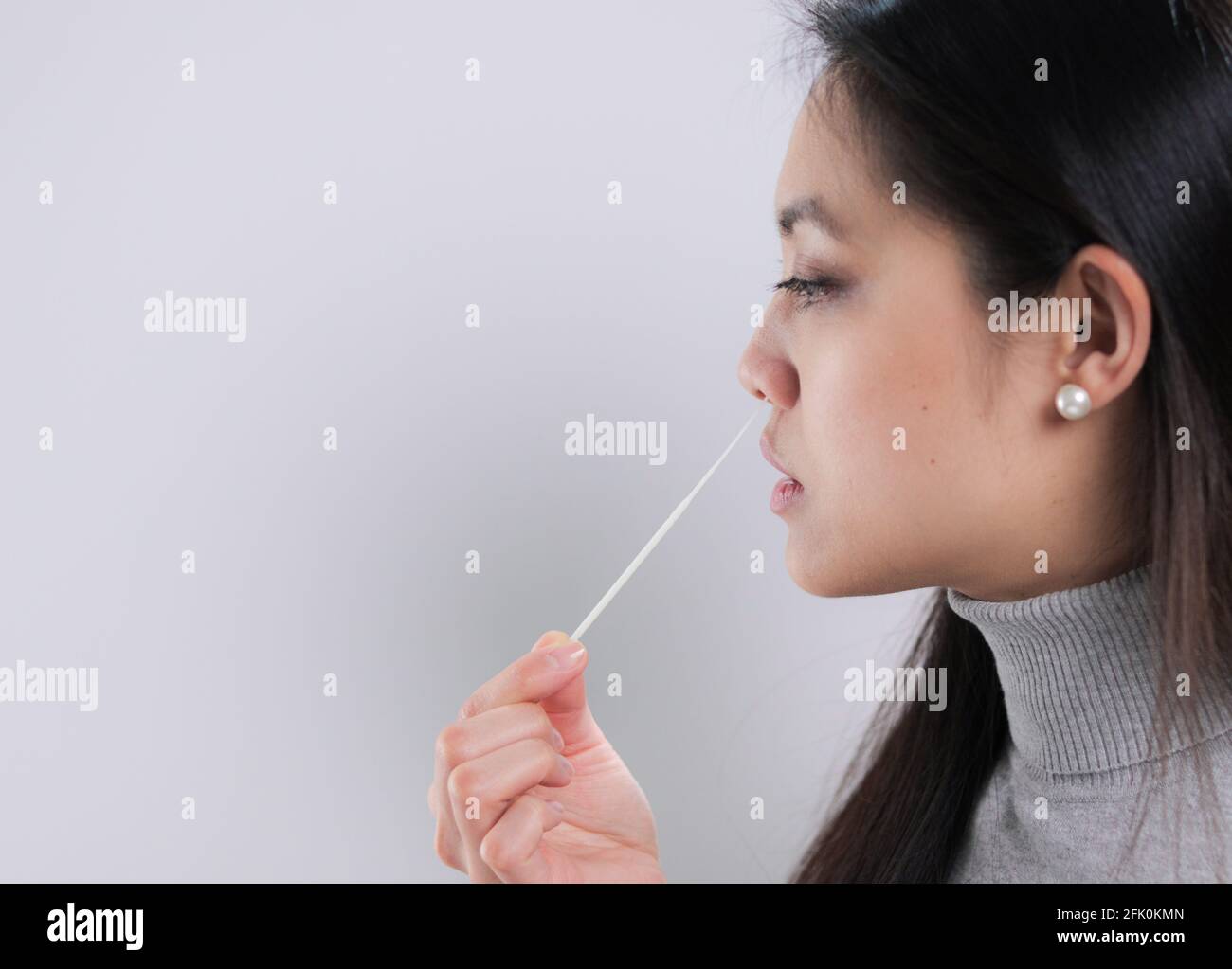 Giovane donna prende un campione dal suo naso per un test corona Foto Stock