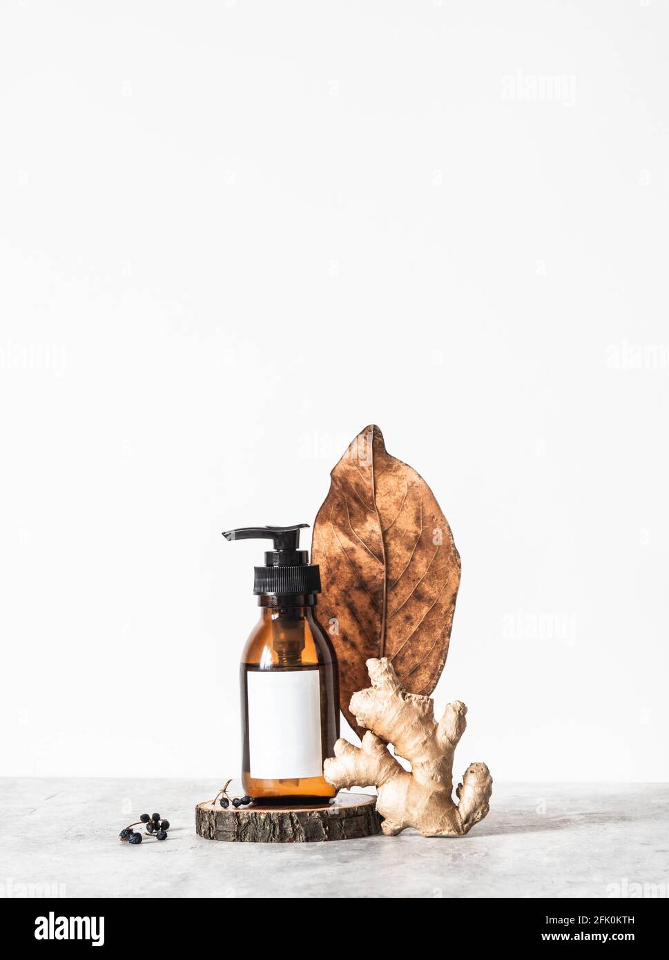 Composizione creativa di tendenza da bottiglia di vetro cosmetico marrone con etichetta bianca e vari ingredienti naturali su sfondo bianco. Vista frontale. Copia sp Foto Stock