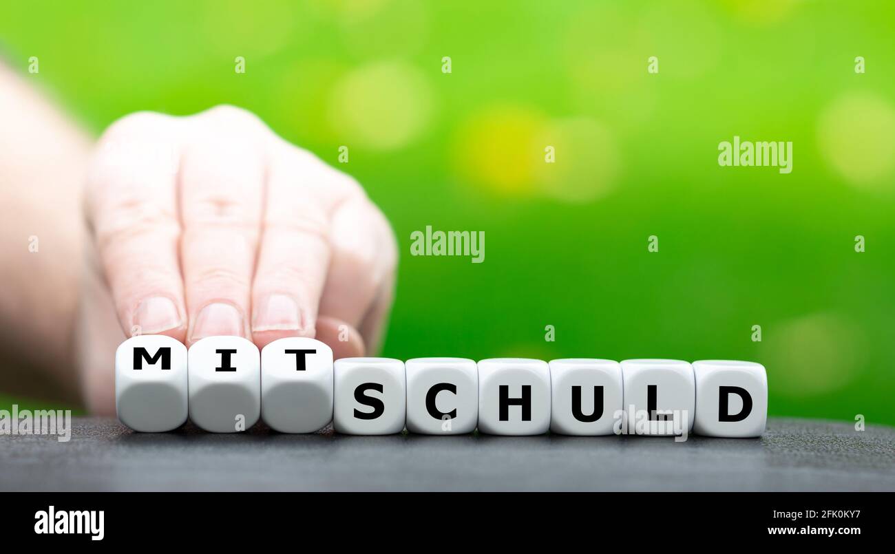 La mano trasforma i dadi e cambia la parola tedesca 'Schuld' (gilt) in 'ditschuld' (gilt congiunta). Foto Stock