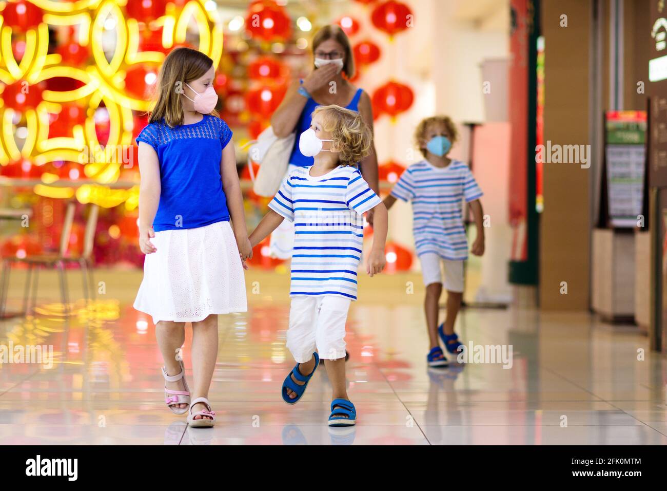 La famiglia indossa la maschera facciale nel centro commerciale in Asia. Madre e bambini indossano il facemask durante il coronavirus e l'epidemia di influenza in Cina. Foto Stock