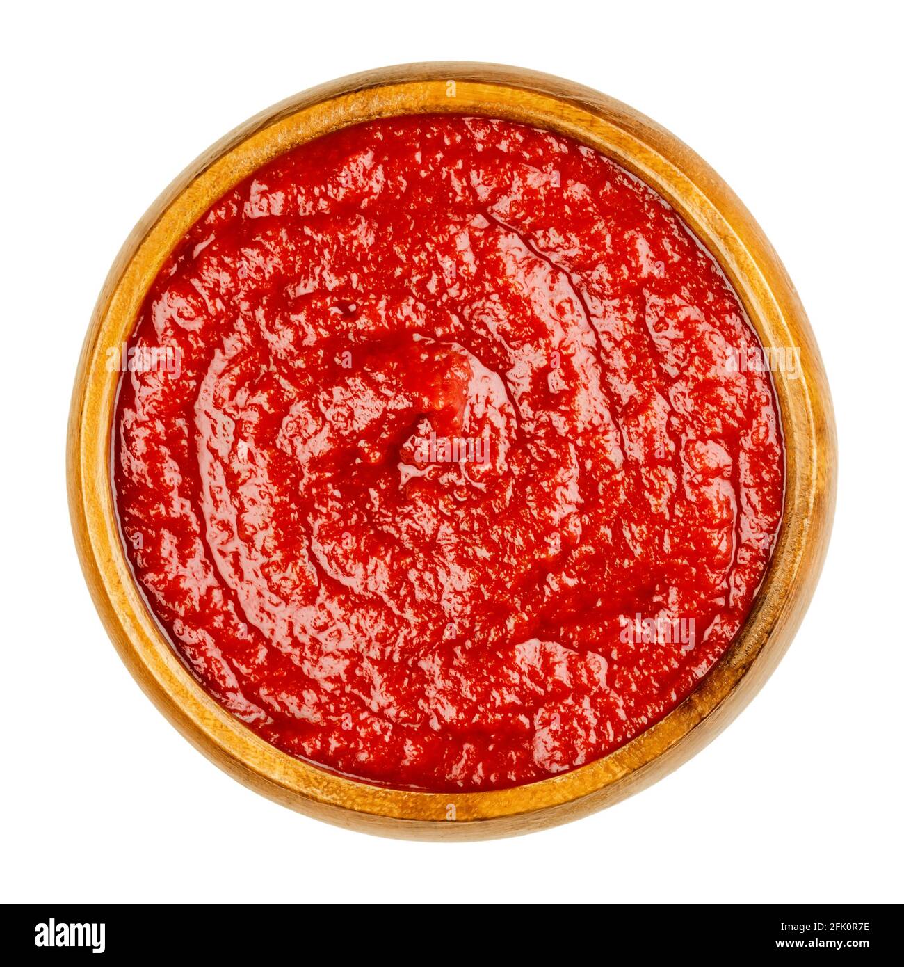 Ketchup di pomodoro fatto in casa in una ciotola di legno. Condimento da tavola rosso dolce e piccante, composto da pasta di pomodoro, zucchero, aceto e condimenti. Foto Stock