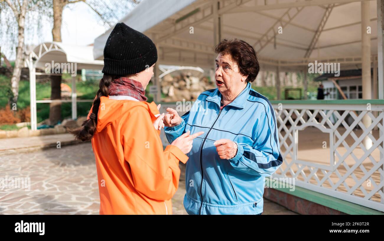 Una nonna e una nipote adulta comunicano per strada. All'aperto. Il concetto del rapporto tra generazioni. Foto Stock