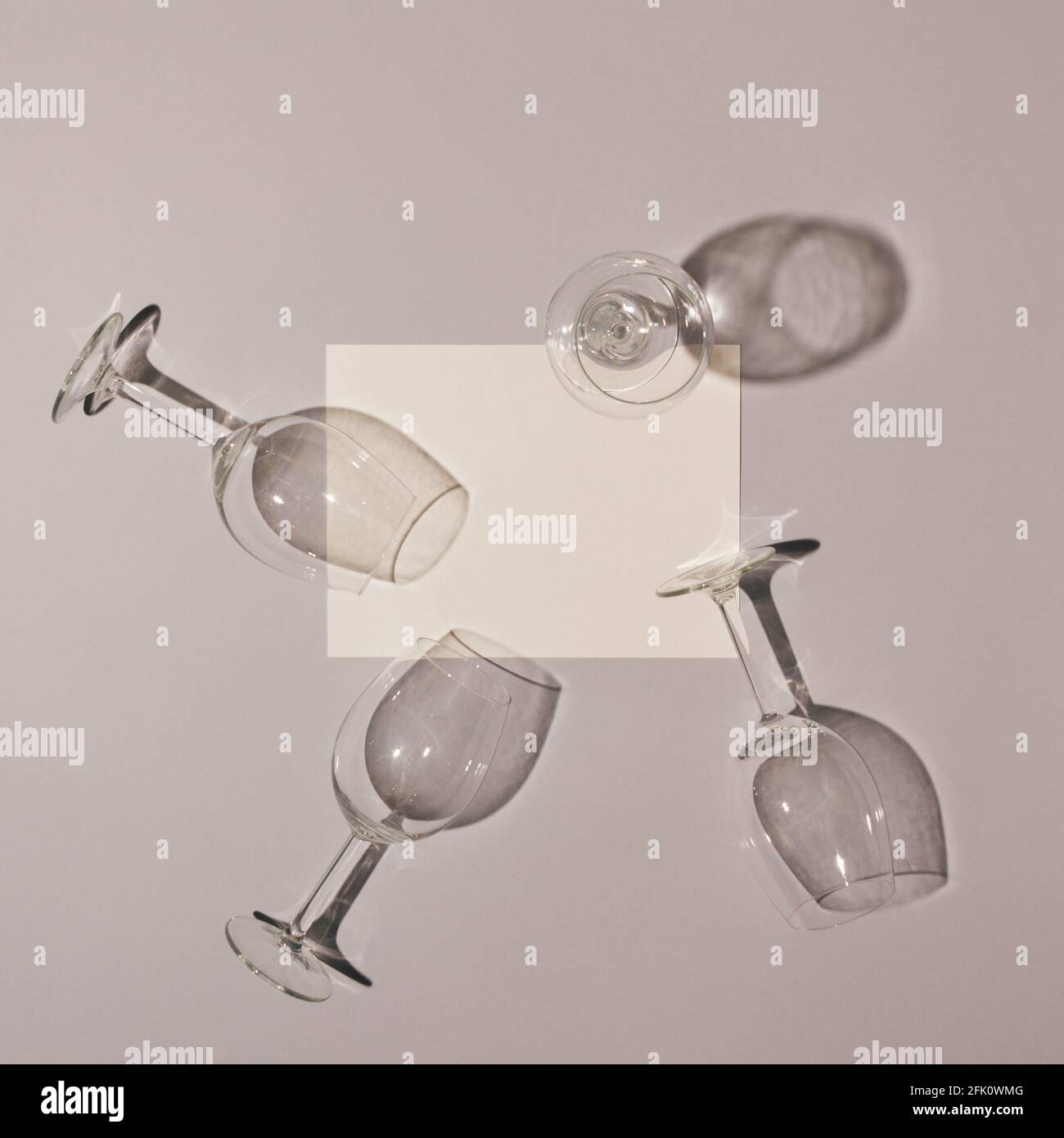 Bicchieri da vino vuoti con ombre e cartoncino di carta bianca su sfondo grigio. Minima idea estetica. Foto Stock