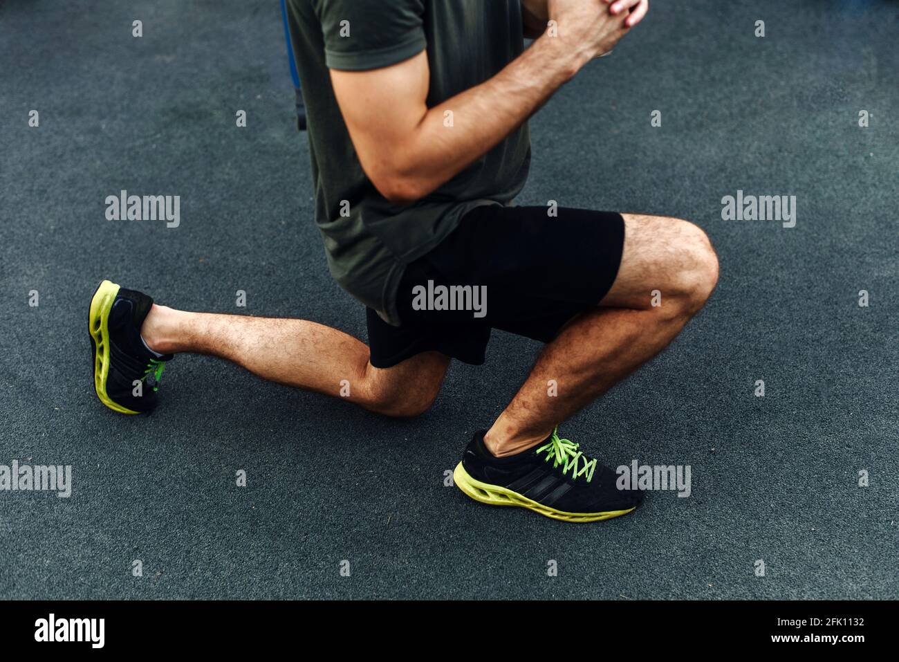 Atleta giovane e sano che fa squat sul parco giochi per strada. Giovane uomo che si esercita all'esterno. Primo piano. Foto Stock