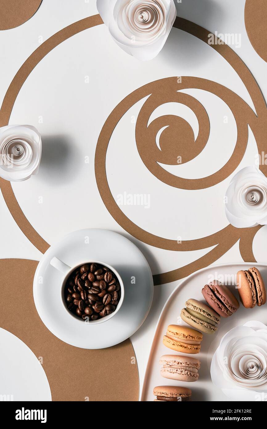 Chicchi di caffè in tazza, macaron, cerchi di sequenza Fibonacci. Espresso, gustosa perfezione. Concetto di rapporto d'oro, arte della carta Vista dall'alto in due tonalità, bianco Foto Stock