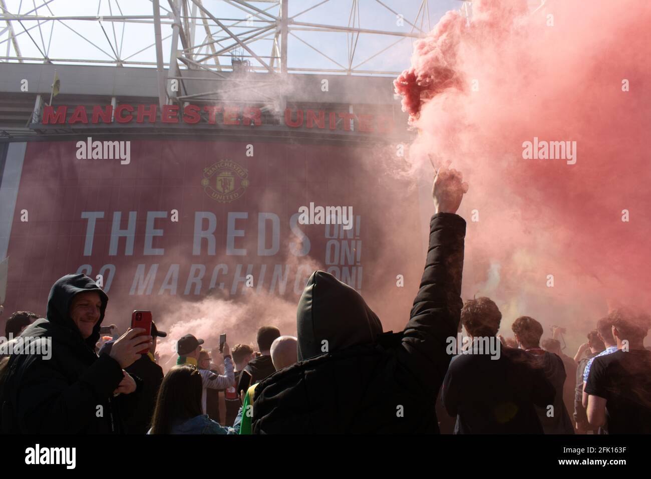 Protesta contro Glazer al campo di football Old Trafford . Sostenitore che tiene la luce rossa del fumo. Testo dei farmaci visibili. Stadio Manchester United, Regno Unito. Foto Stock