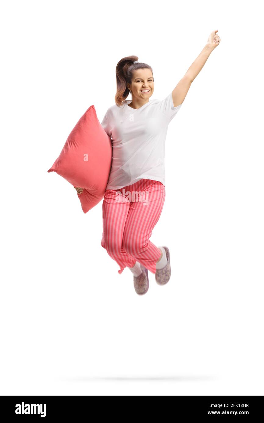 Donna felice in pigiama che tiene un cuscino e salta in su isolato su sfondo bianco Foto Stock