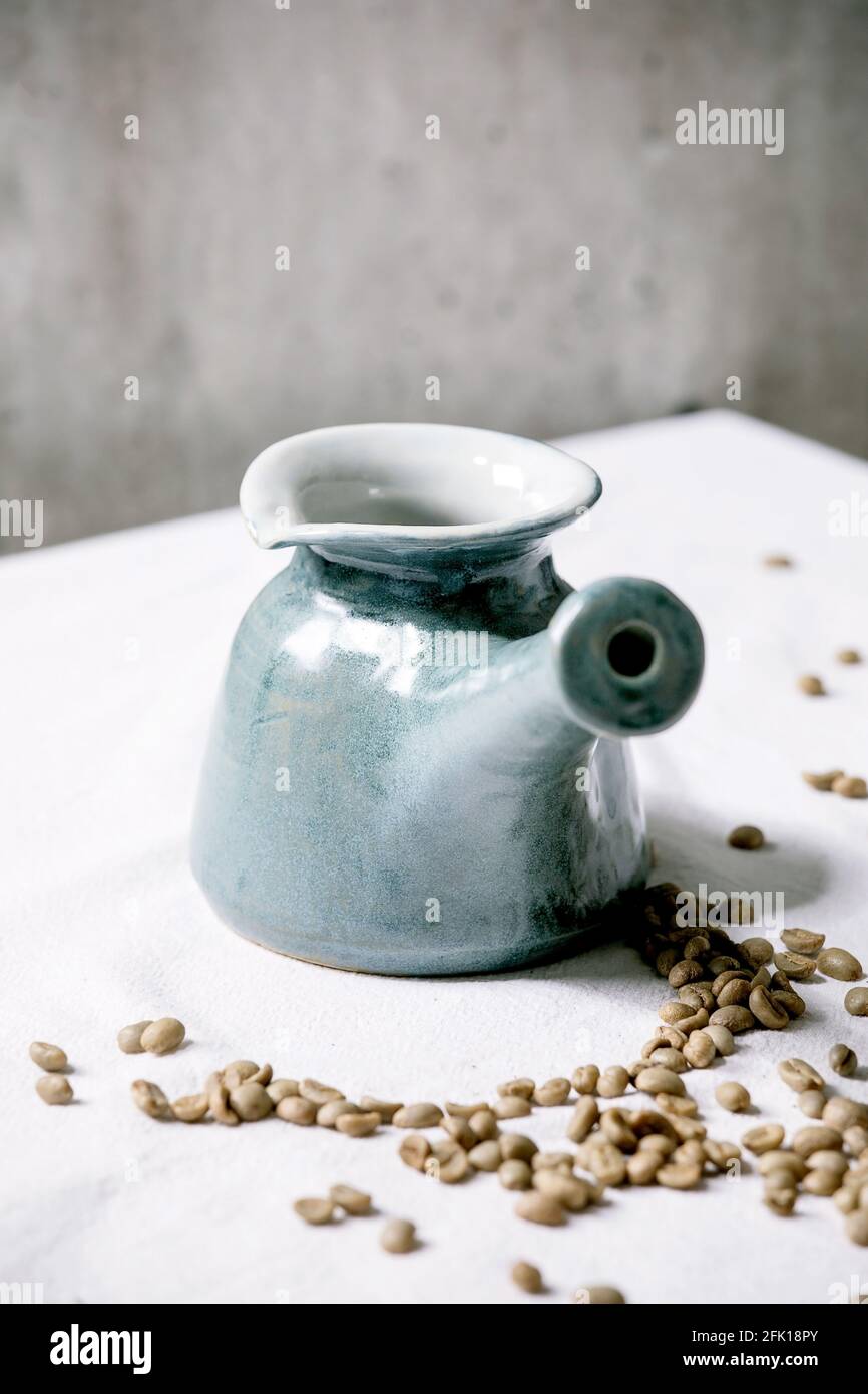 Caffettiera in ceramica artigianale blu cezve turco in piedi su tovaglia  bianca con chicchi di caffè sopra. Parete grigia dietro. Spazio di copia  Foto stock - Alamy