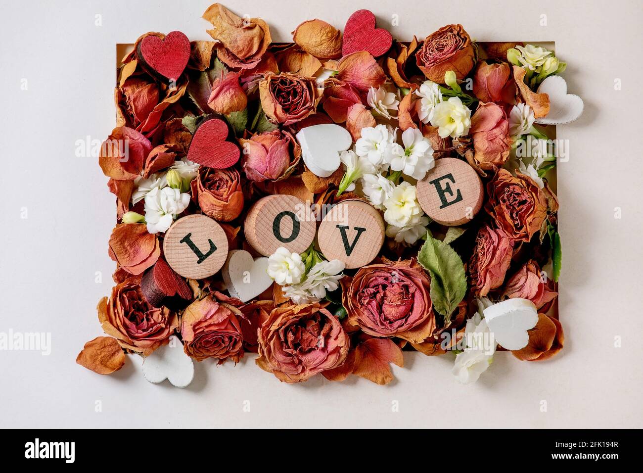 Bella composizione botanica per st. San Valentino. Layout creativo con rose secche, petali, fiori bianchi, cuori piccoli e lettere D'AMORE in bianco Foto Stock