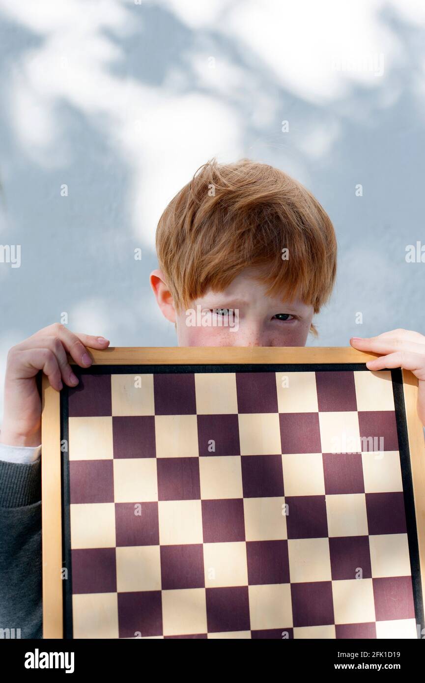 il bambino con i capelli rossi gioca a scacchi Foto Stock