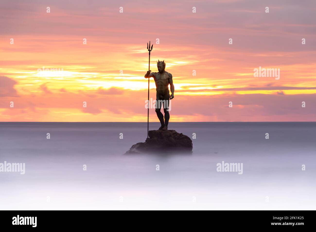 Immagine a lunga esposizione della statua del Dio Nettuno tra acque lisce a Melenara Beach sull'isola di Gran Canaria (Spagna) all'alba. Concetto di viaggio Foto Stock